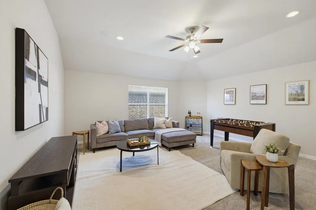 Vaulted ceiling with a ceiling fan, recessed lighting, and a window with brick exterior visibility