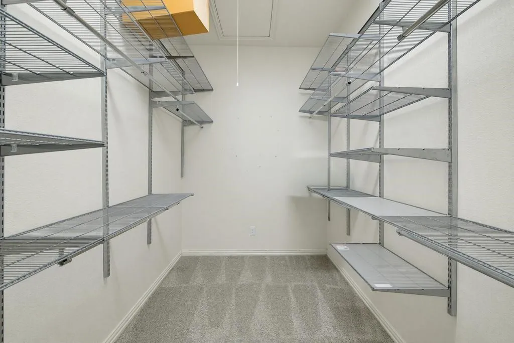 Carpeted room featuring adjustable wire shelving and built-in storage