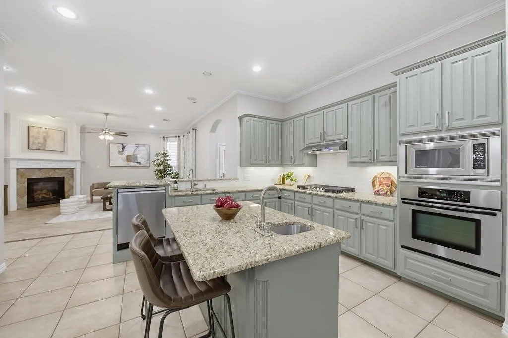 Kitchen with light-toned cabinetry, granite countertops, stainless steel appliances, and tile flooring