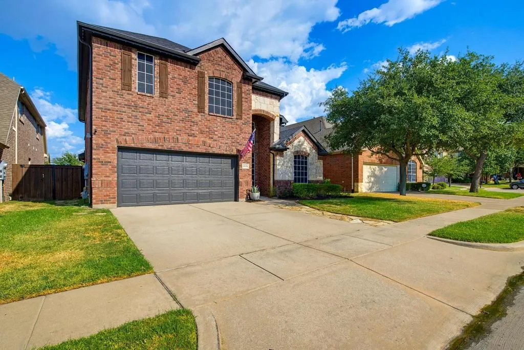 Brick exterior with stone accents, arched window, dark garage door, and a concrete driveway