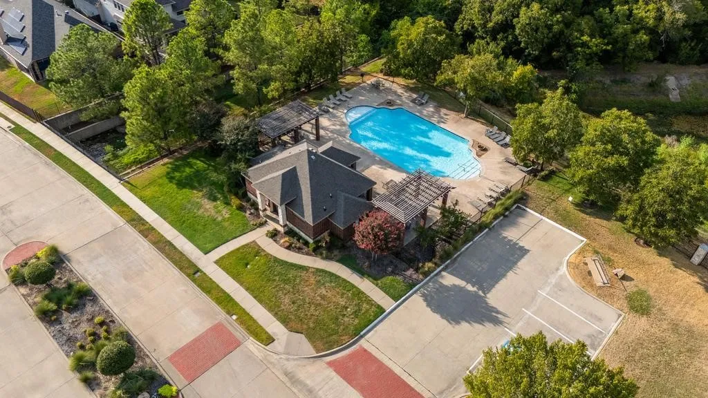 Community pool with a structured pool house, surrounding pergolas, and adjacent parking