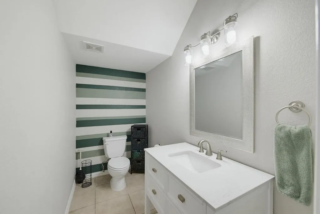White vanity with integrated sink, coordinating wall mirror, and modern light fixture
