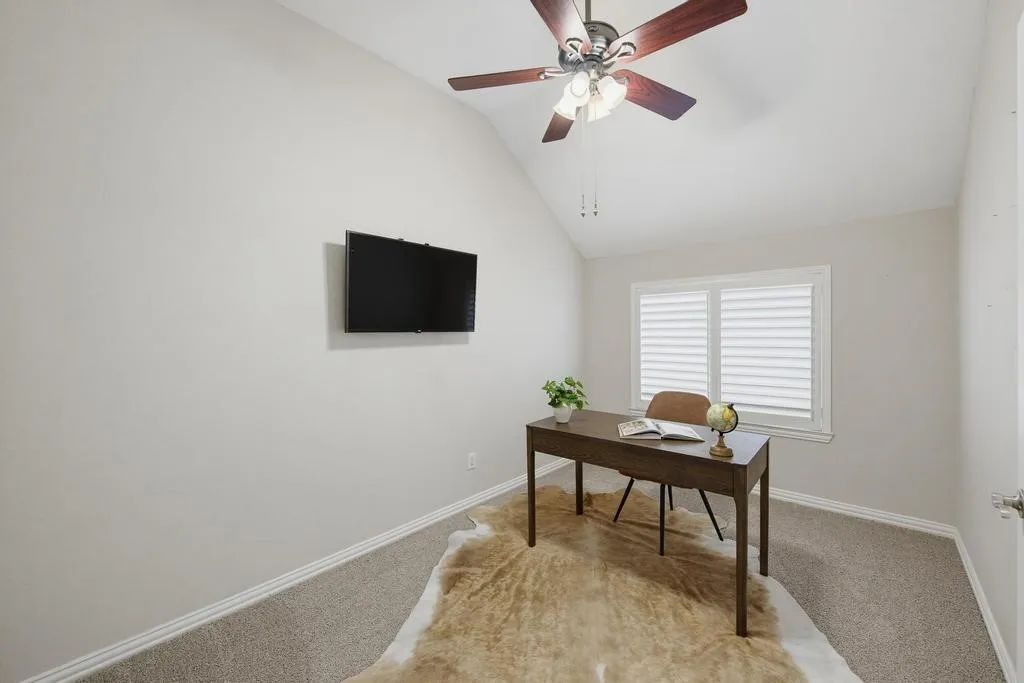 Vaulted ceiling featuring a ceiling fan with integrated lighting, window with horizontal blinds, and wall-to-wall carpeting