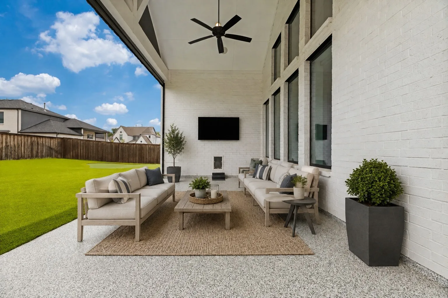 Covered patio with a high ceiling, exposed aggregate flooring, and white brick walls