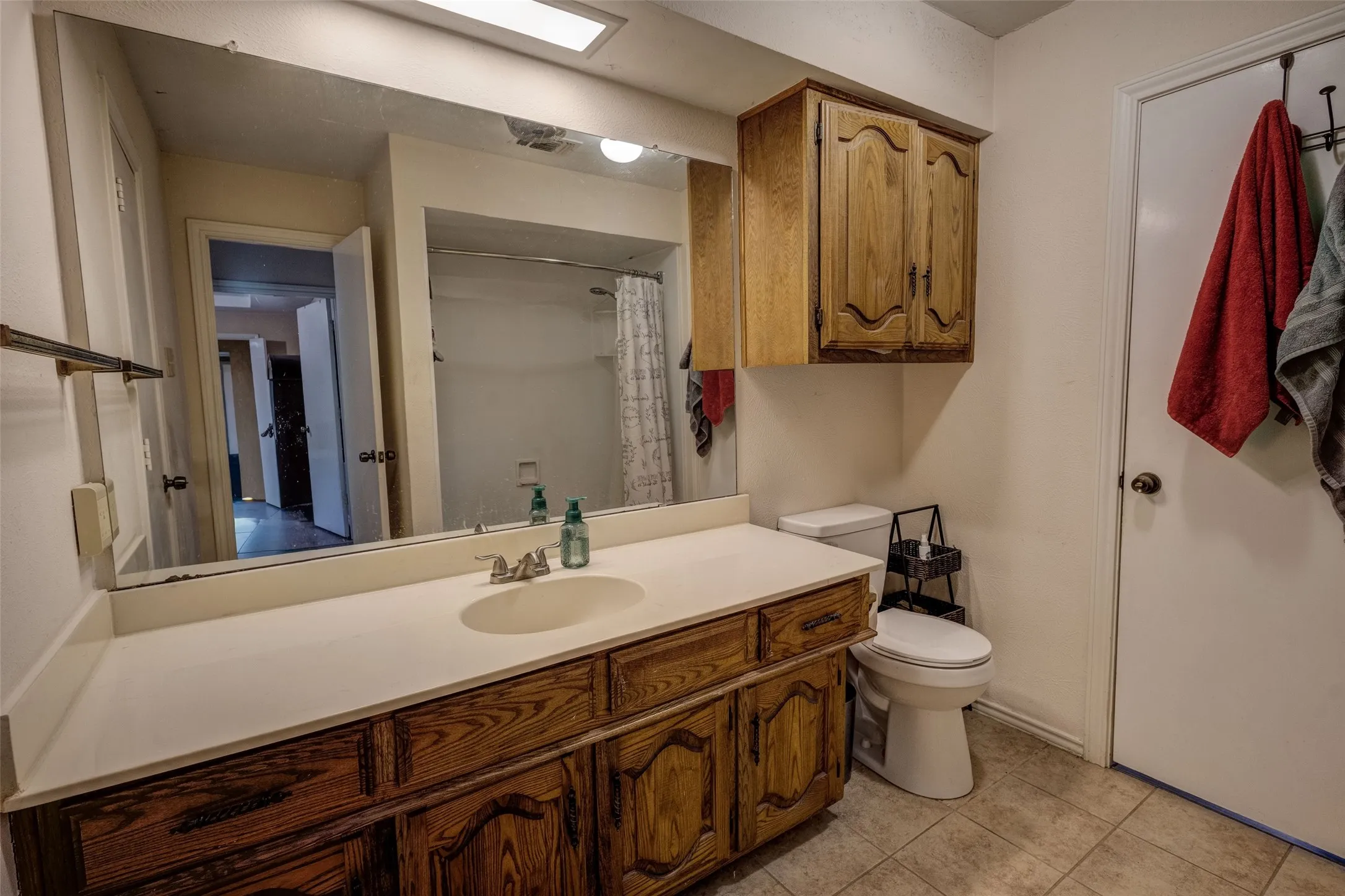 Bathroom featuring a wood-finish vanity with a single sink, an integrated countertop, and a wall-mounted mirror