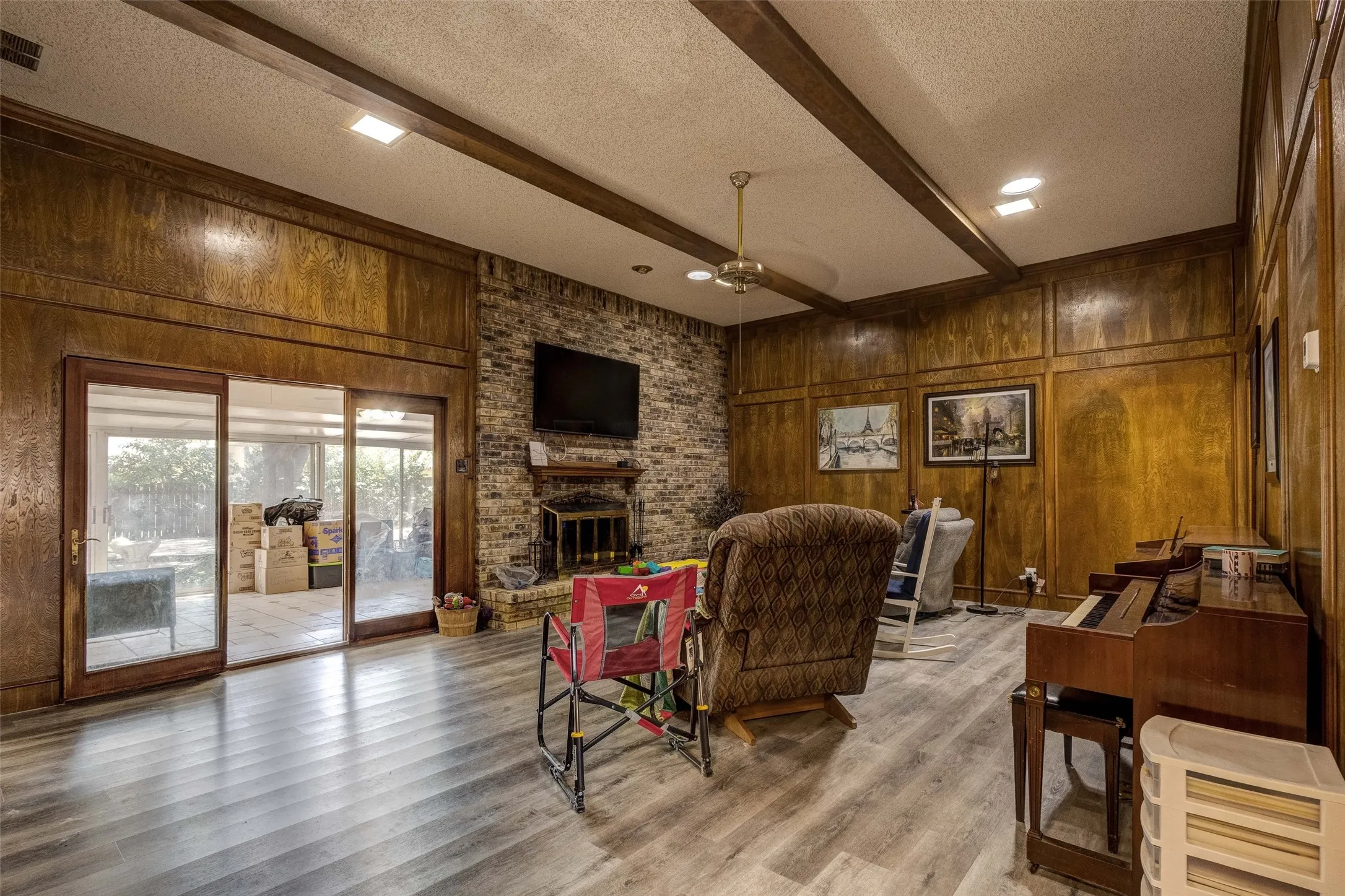 Expansive living area with wood-finish flooring, exposed ceiling beams, and recessed lighting