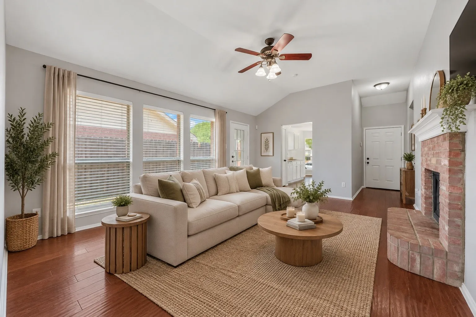 Vaulted ceiling, ceiling fan, brick fireplace, wood-finish flooring, multiple windows