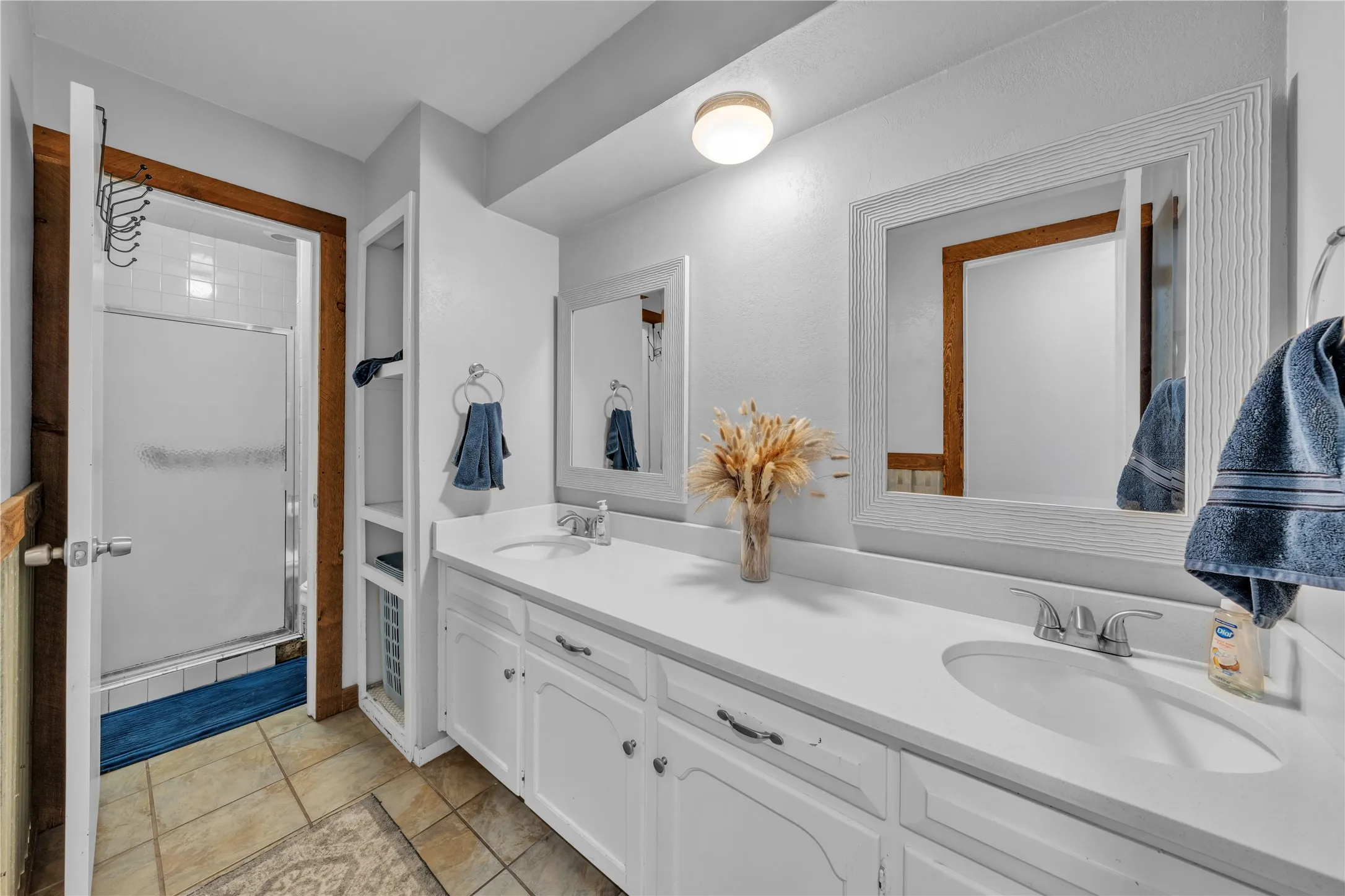 Dual vanity with integrated sinks, white cabinetry, and framed mirrors