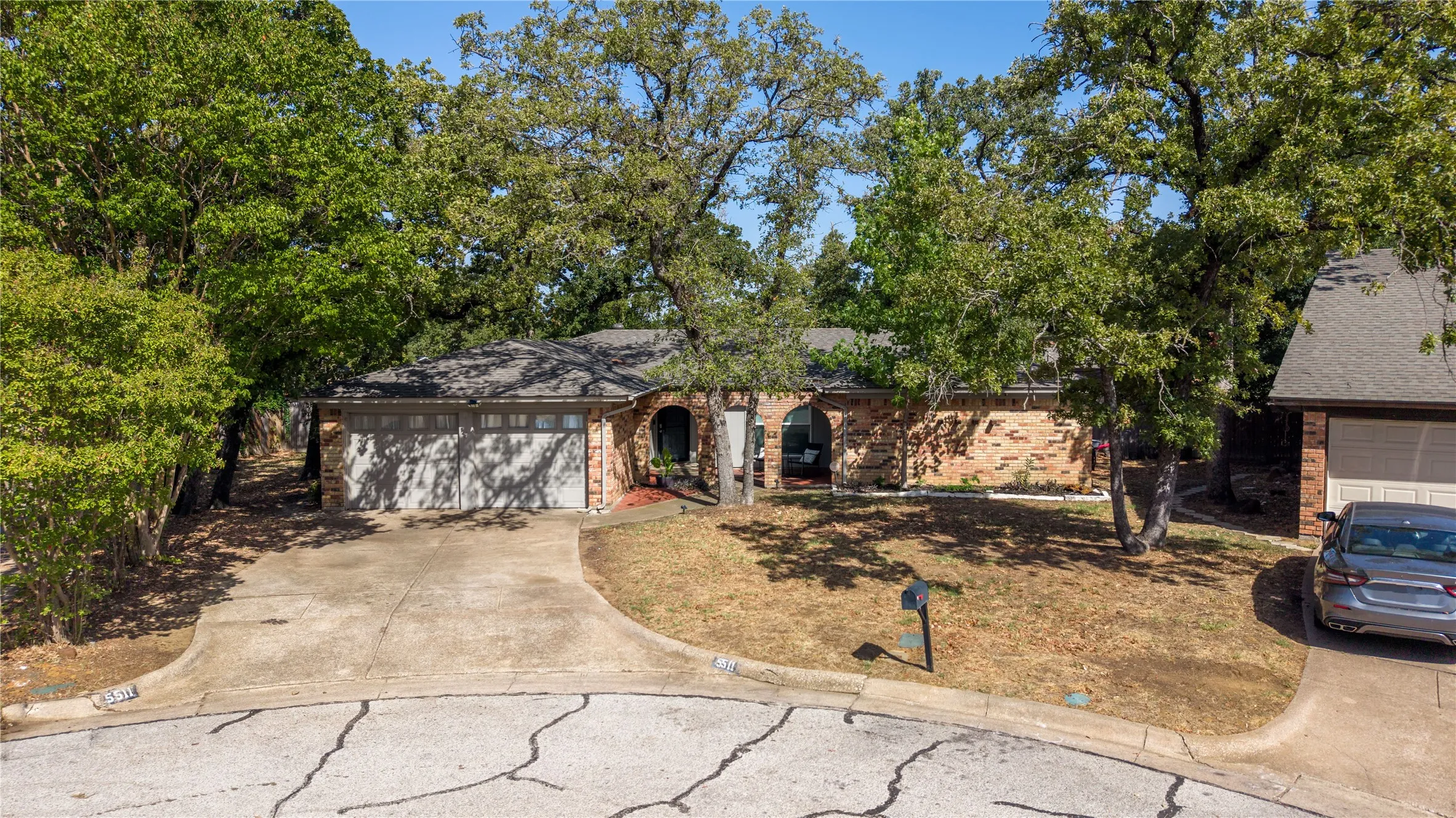 Brick exterior with a prominent arched entry, surrounded by mature trees