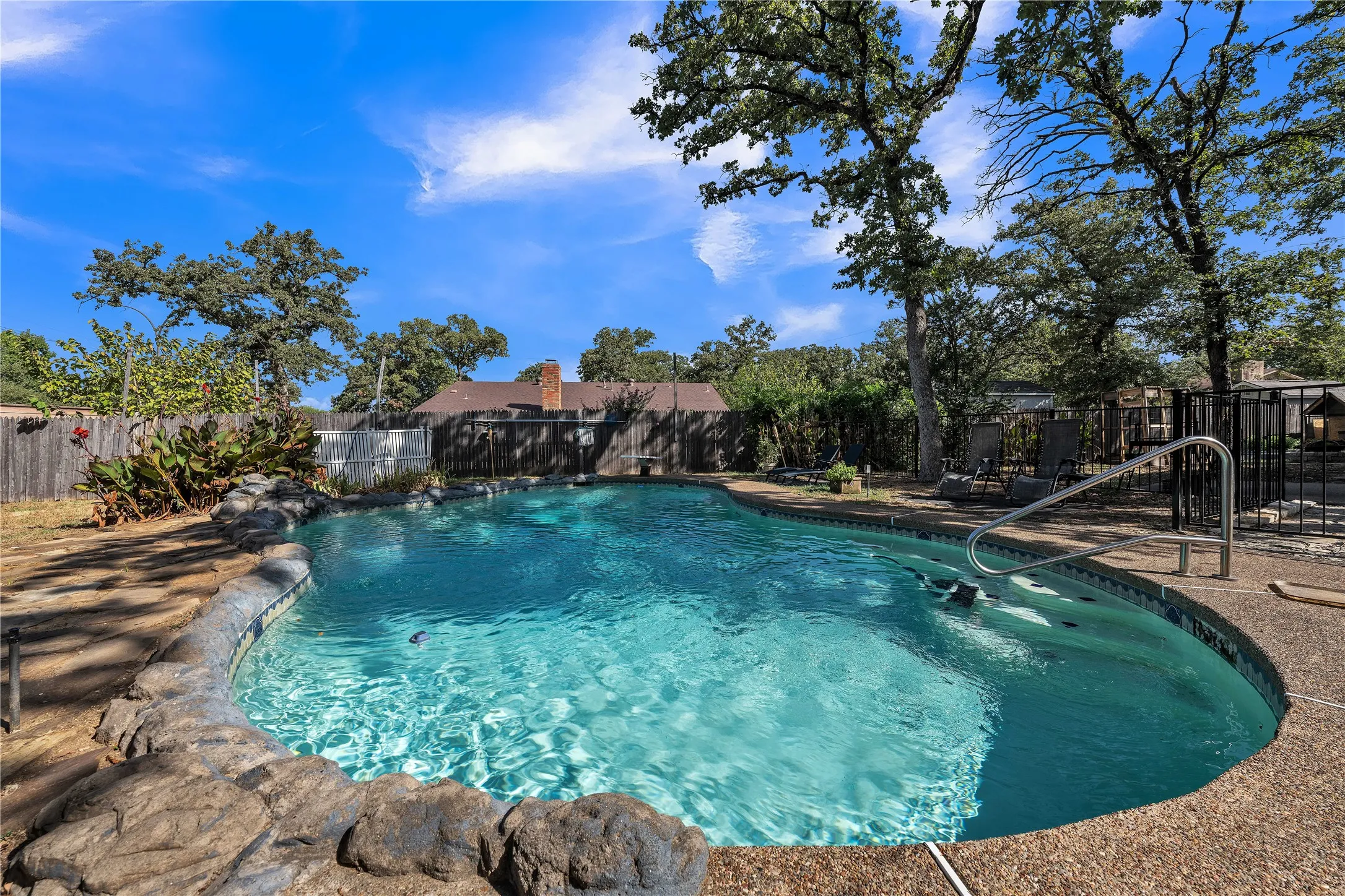 Freeform swimming pool with rock coping and a textured deck surround
