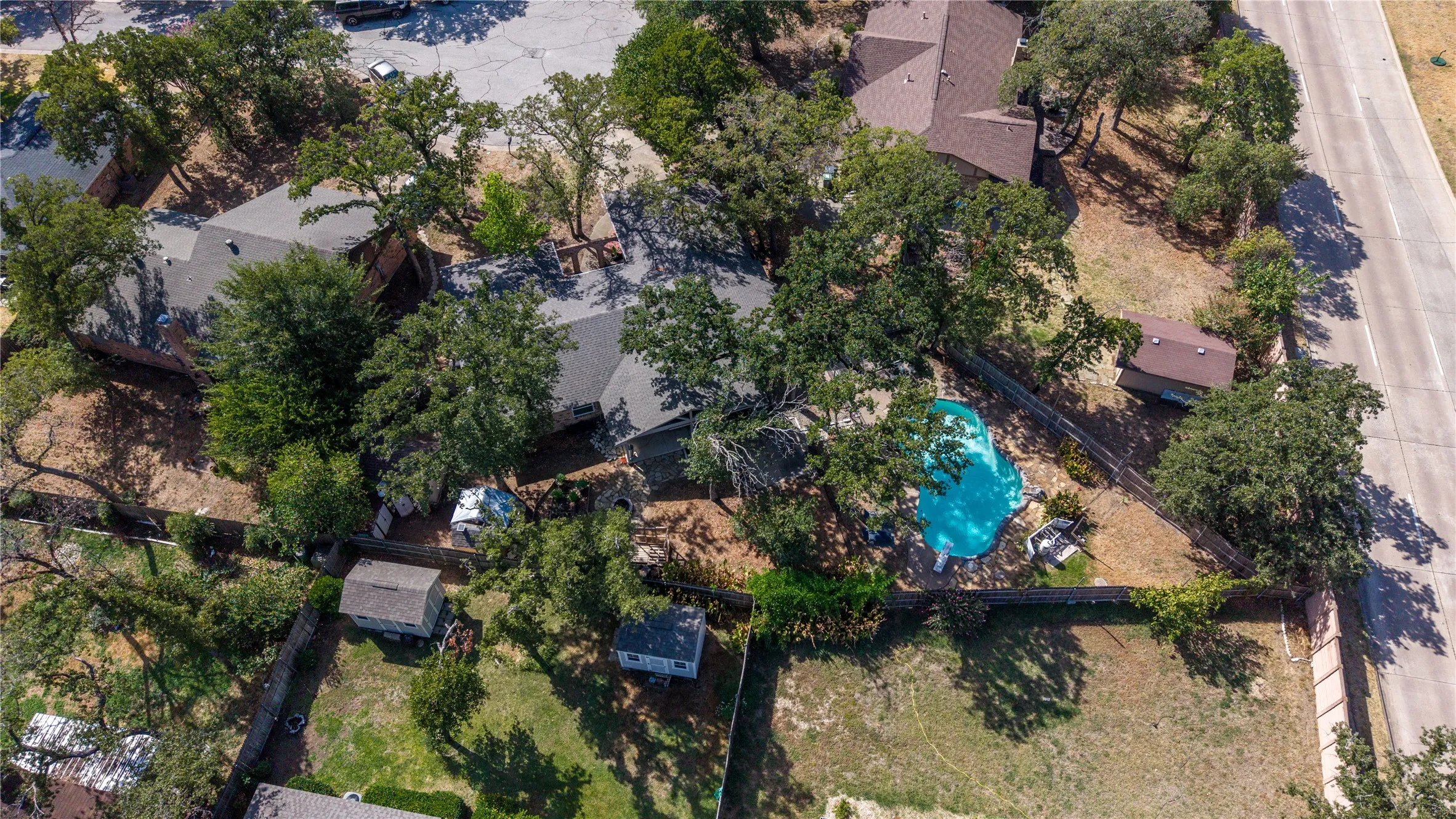 Expansive lot featuring mature trees, a covered swimming pool, and a storage shed