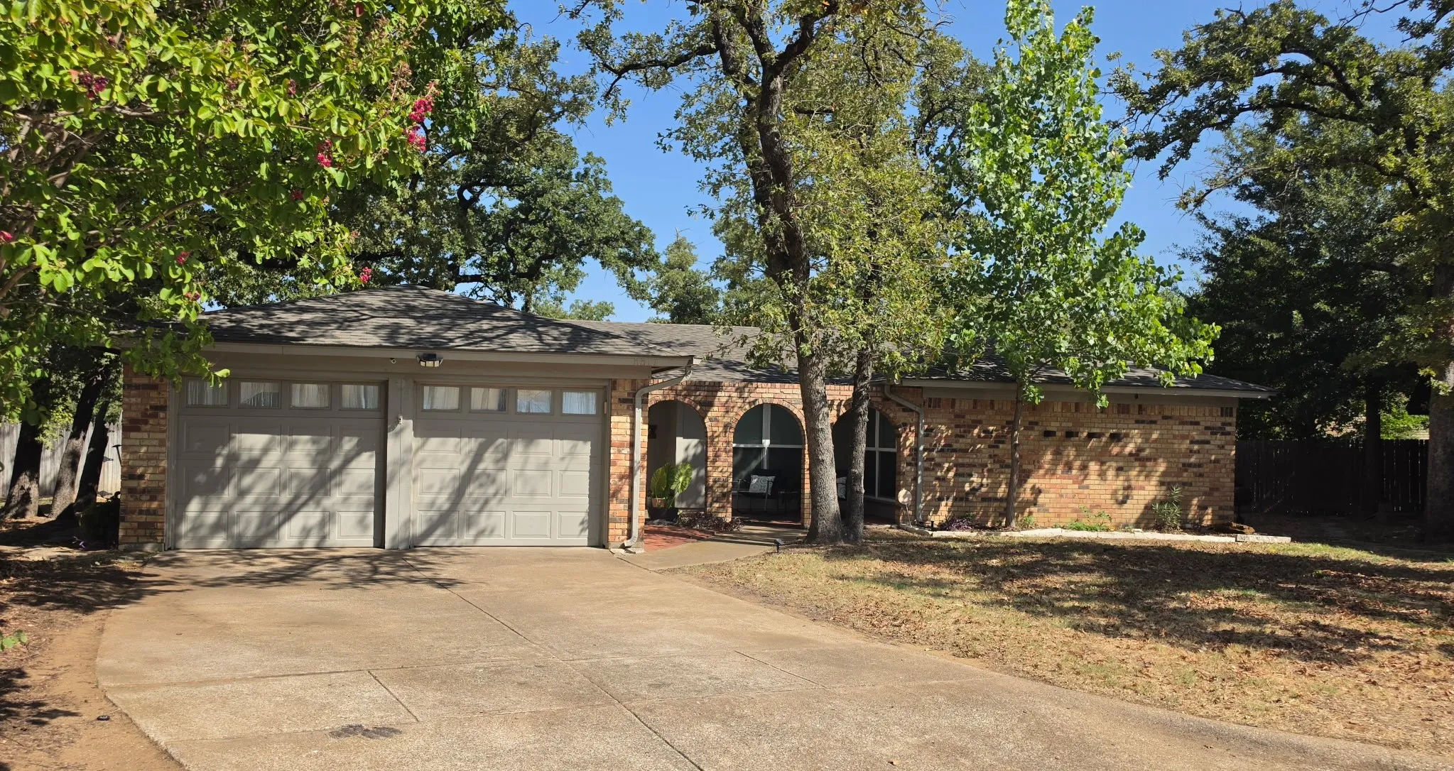 Brick exterior with stone accents, arched entry, two-car garage with transom windows, and a paved driveway