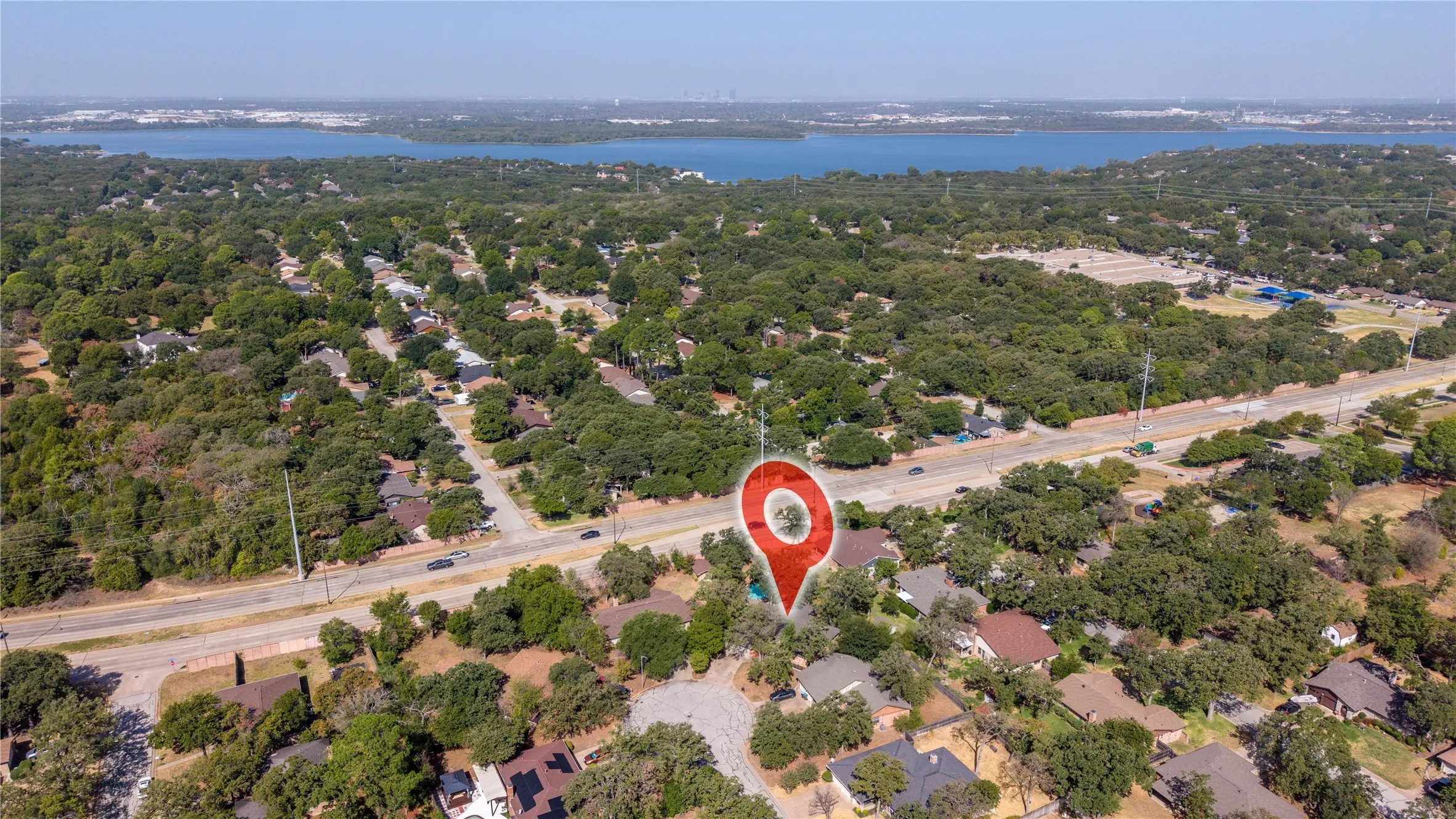Aerial perspective showcasing the residential area with abundant mature trees and proximity to a large body of water