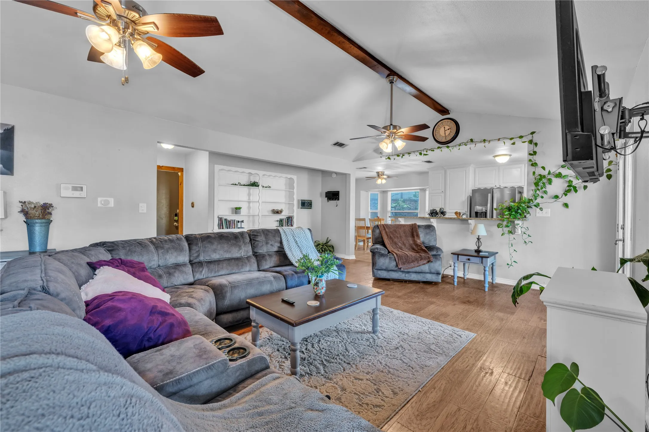Vaulted ceilings with exposed wood beams, wood-finish flooring, and recessed lighting