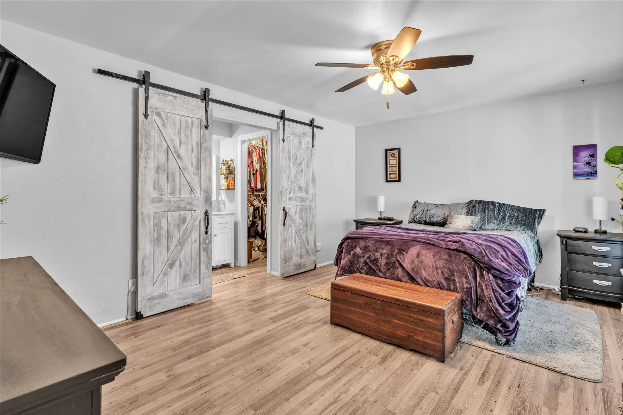 Wood-finish flooring, ceiling fan with integrated lighting, and white walls