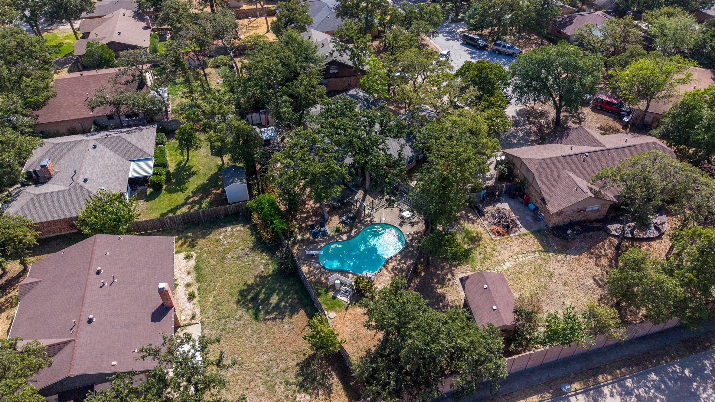 Expansive lot featuring an irregularly shaped inground pool, mature trees, and a detached outbuilding
