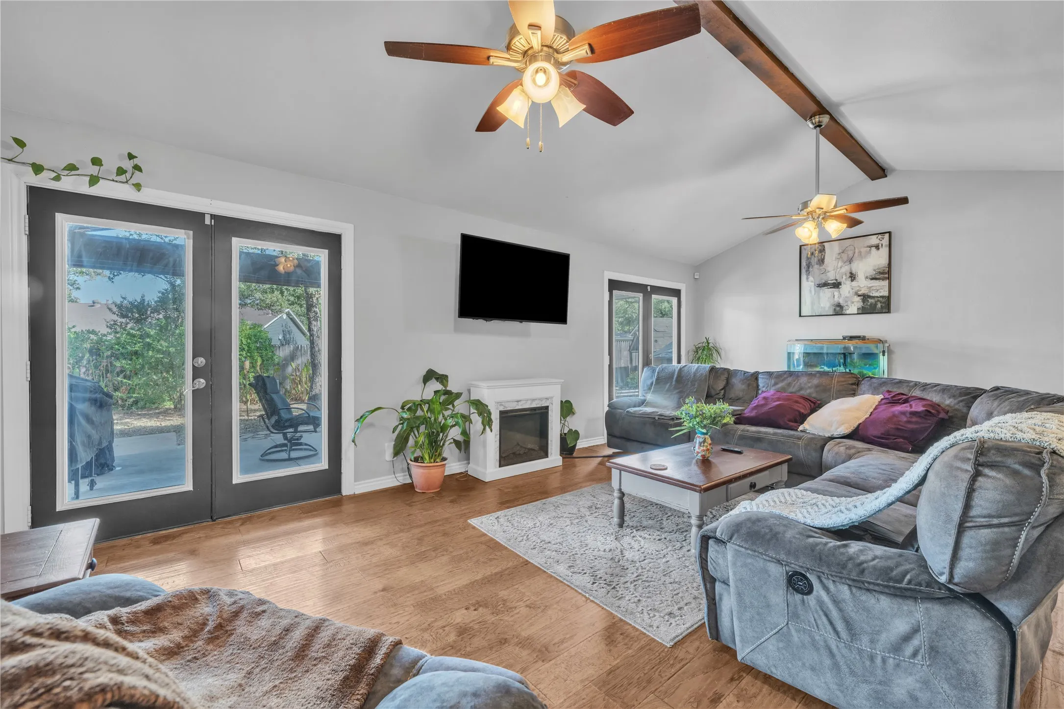 Vaulted ceilings with exposed beams, wood-finish flooring, and white painted walls