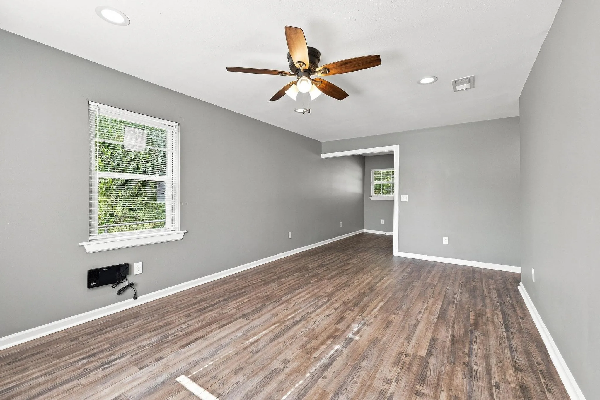 Spacious room featuring wood-finish flooring, a ceiling fan with integrated lighting, and recessed lighting
