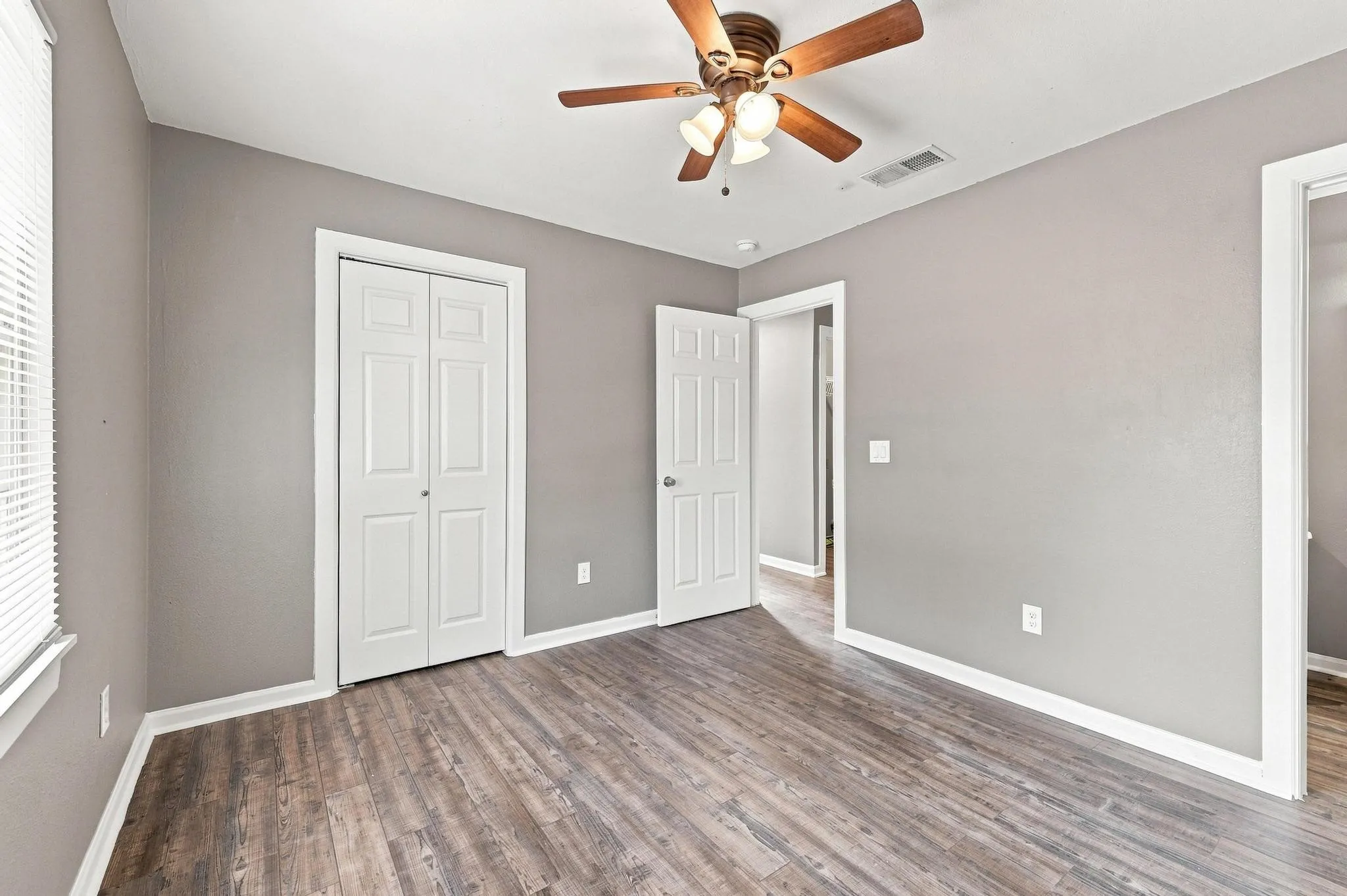 Wood-finish flooring, neutral gray walls, and white trim