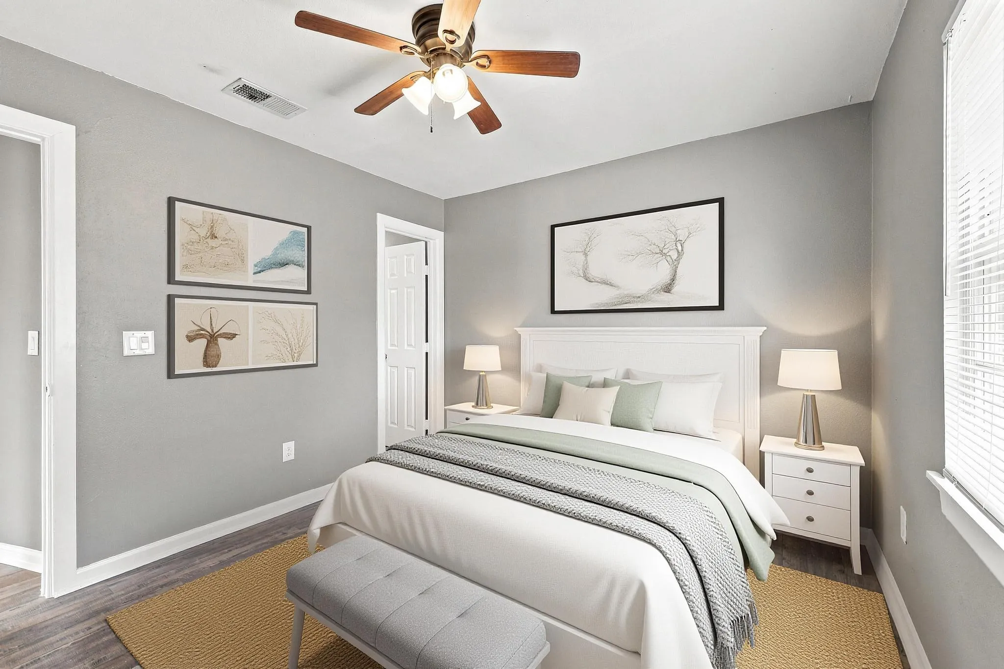 Light gray wall color, wood-finish flooring, white trim, window with blinds, and a ceiling fan with integrated lighting