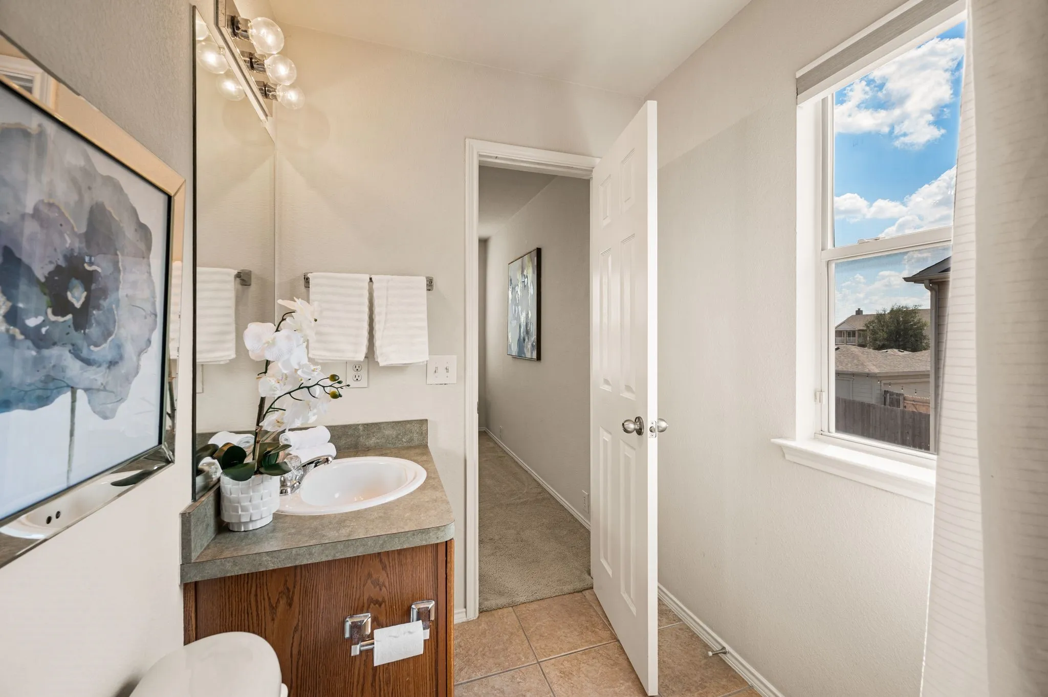 Bathroom featuring a single vanity, undermount sink, countertop, and a window for natural light