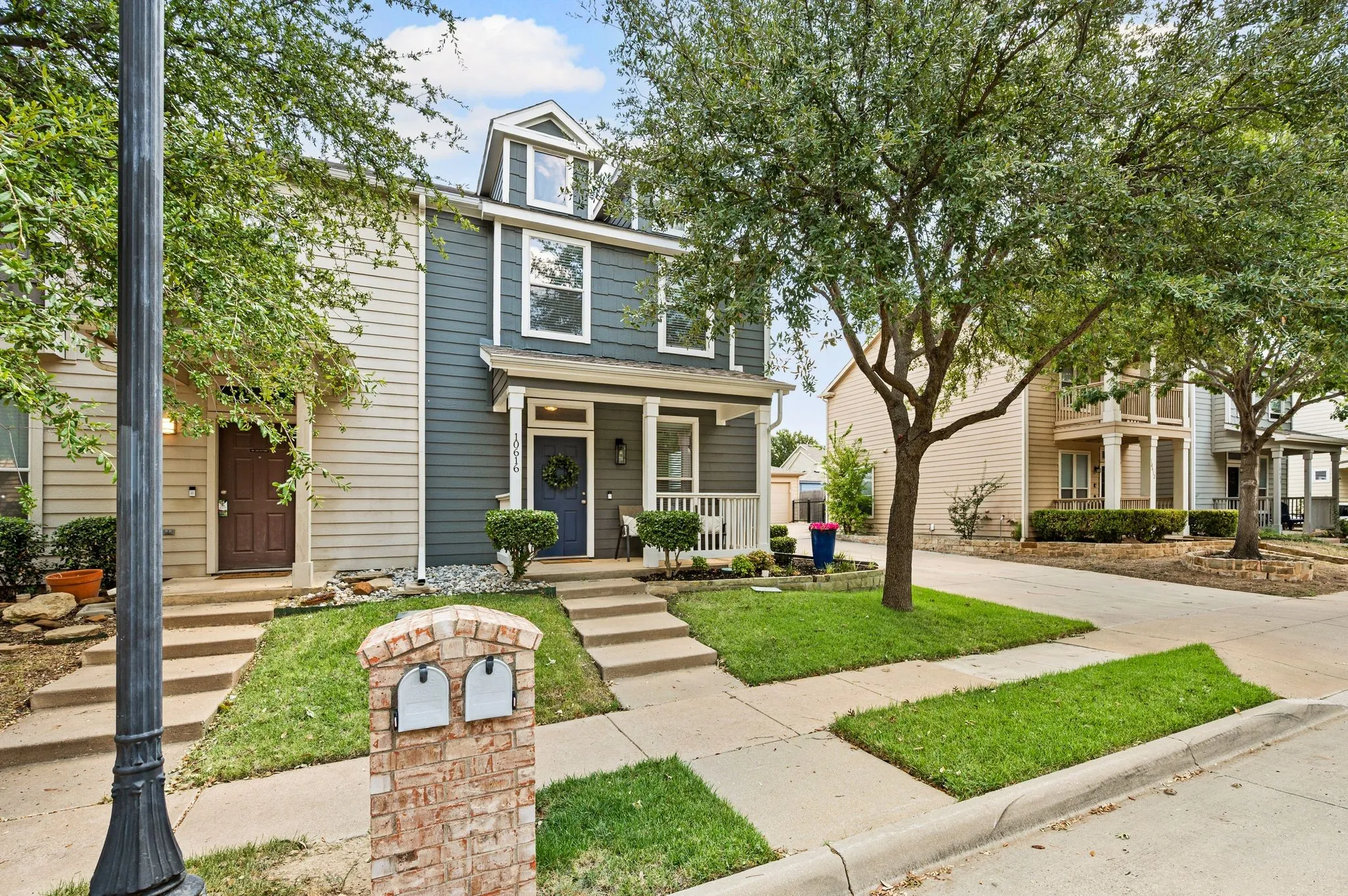 Two-story townhome with dormer window, covered porch, and a brick mailbox