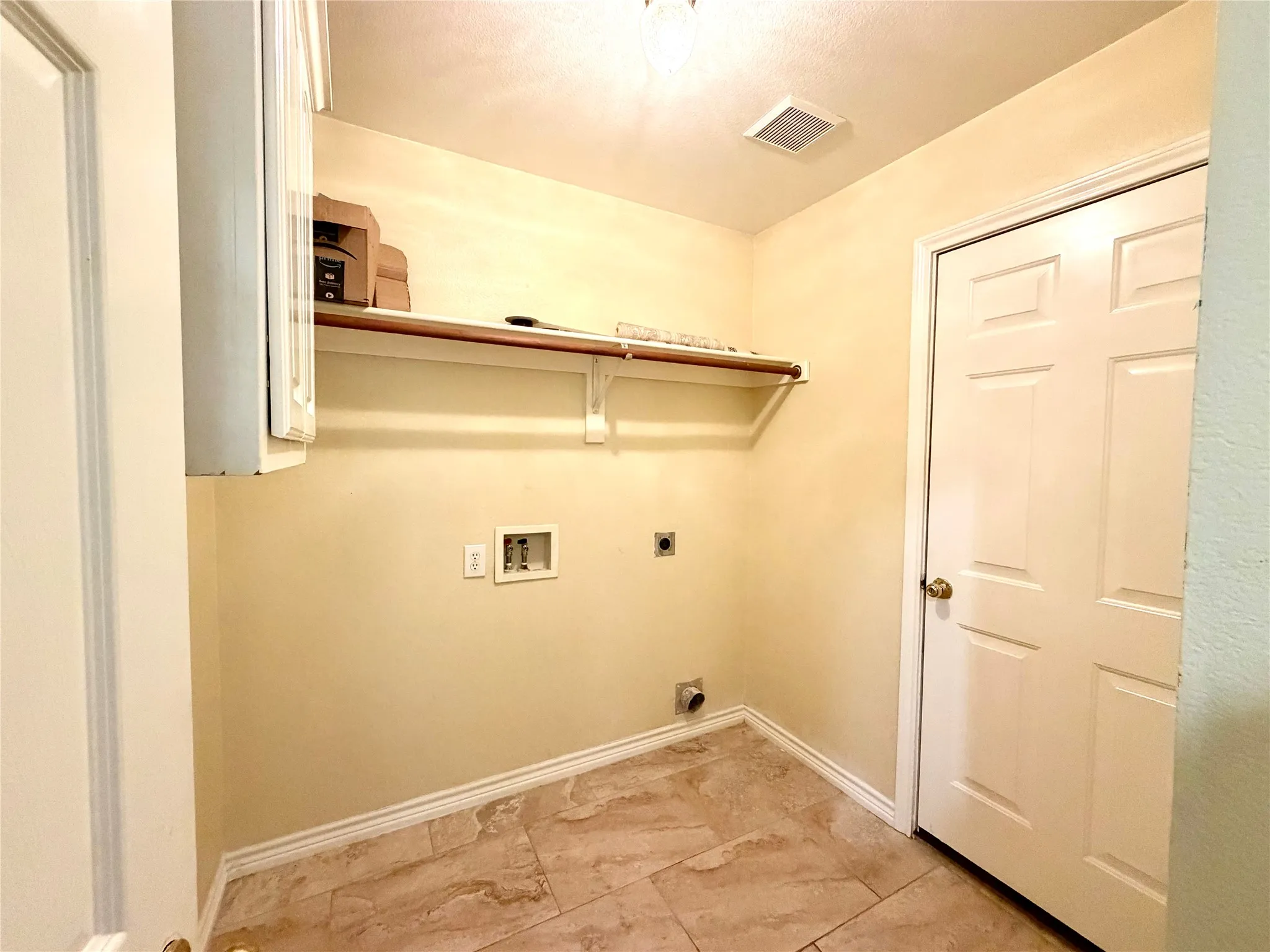 Utility room with tiled flooring, overhead shelving, and a built-in upper cabinet