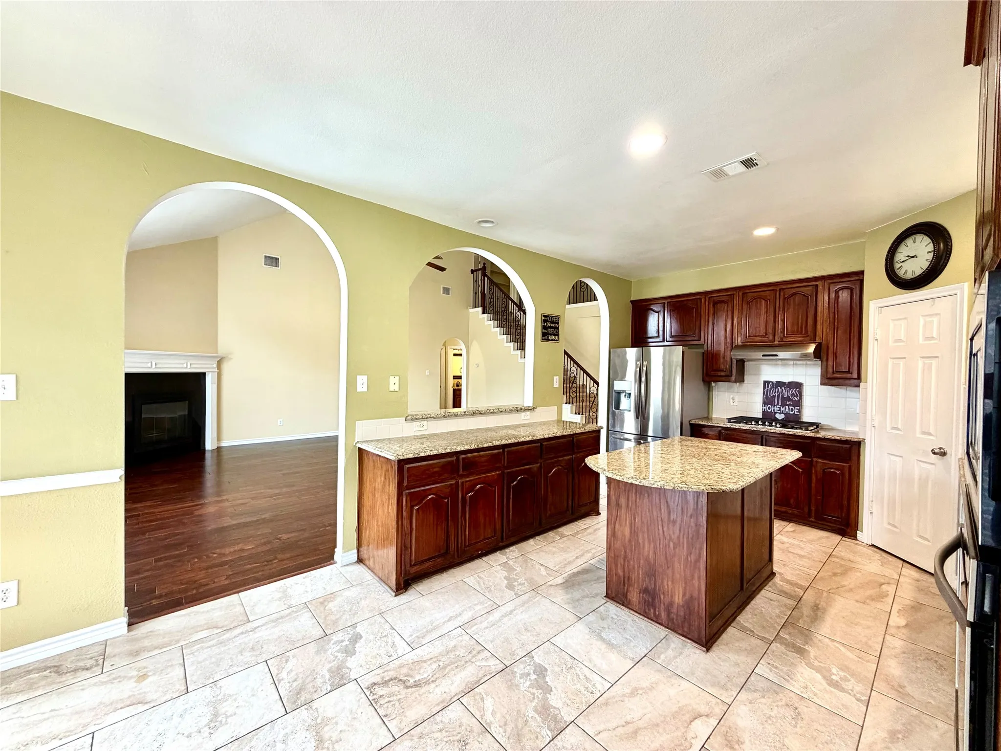 Kitchen with a center island, wood cabinetry, stainless steel appliances, and tile flooring