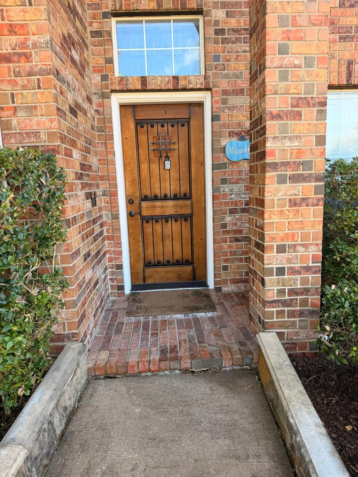 Brick exterior with a detailed wooden front door, transom window, and brick-paved entry