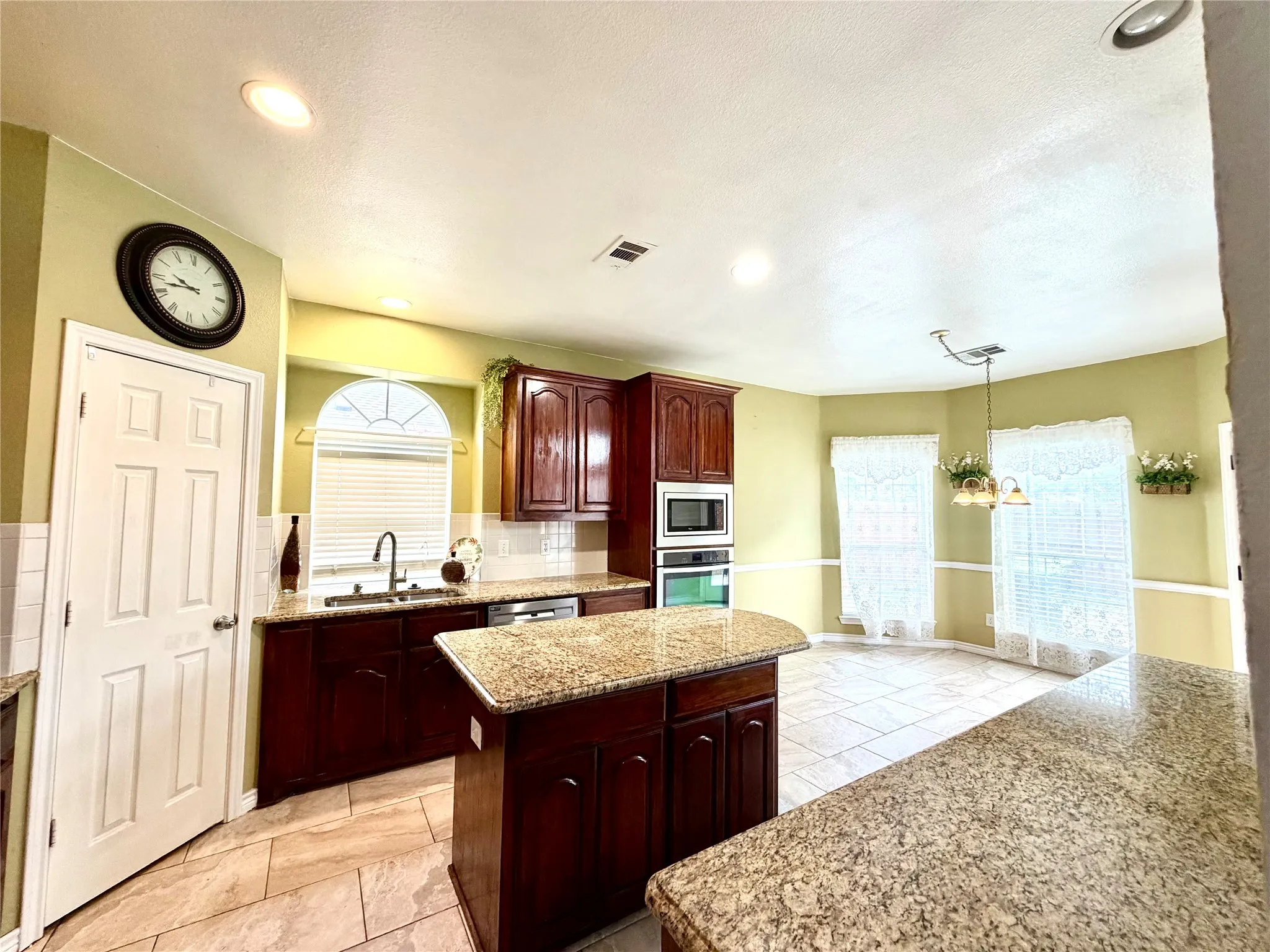 Kitchen featuring recessed lighting, wood cabinetry, stone countertops, a built-in oven and microwave, and tile flooring