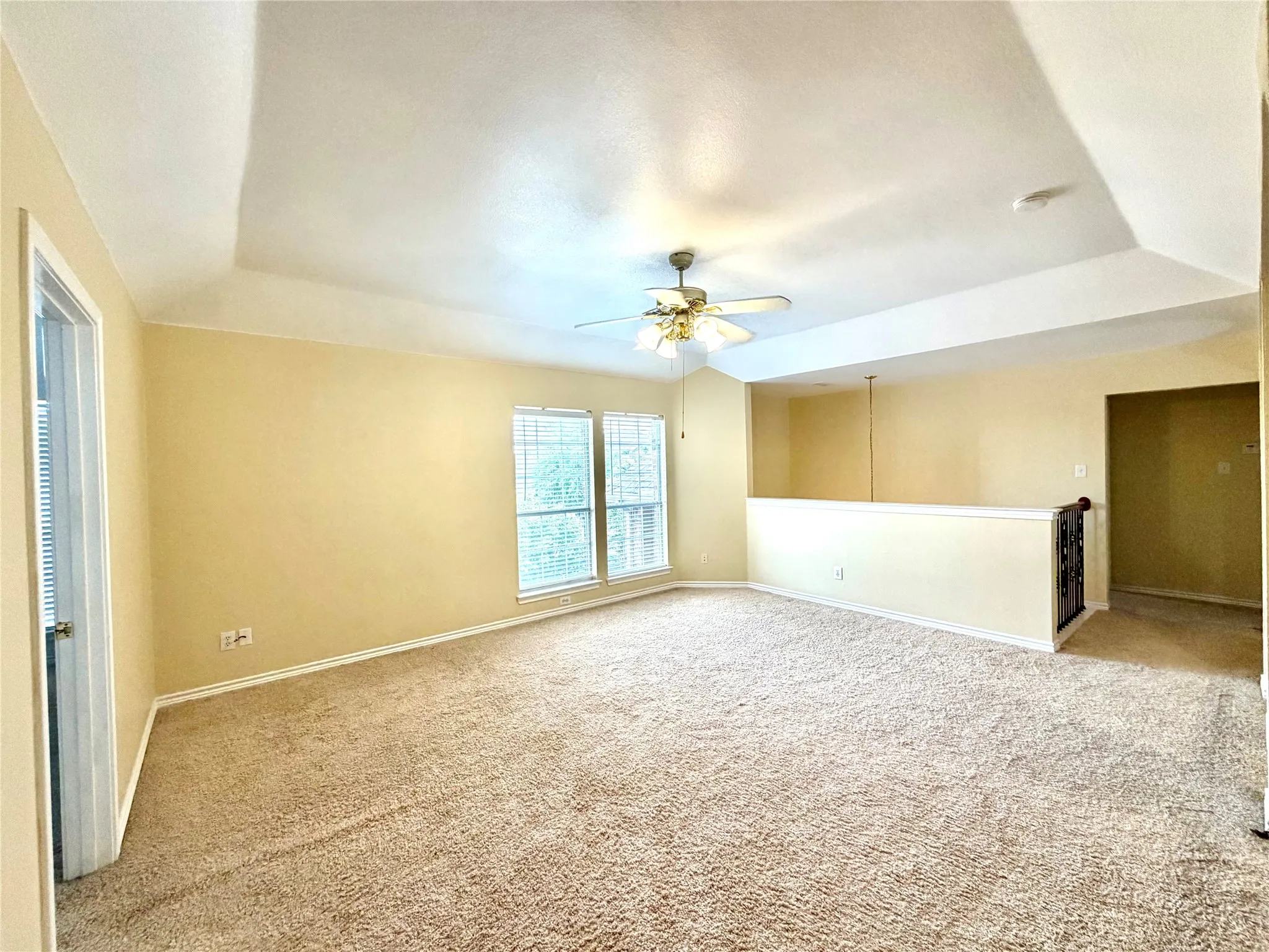 Carpeted interior space with a tray ceiling and ceiling fan