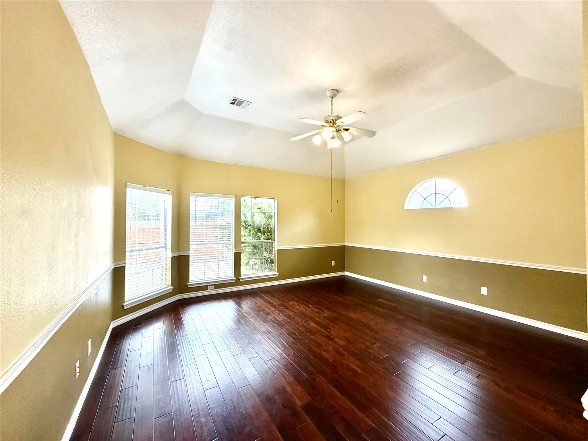 Recessed ceiling with a ceiling fan light fixture, wood-finish flooring, half-round transom window, and a bay window featuring white blinds