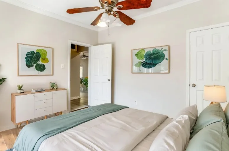 Warm wood-finish flooring, crown molding, and a ceiling fan with integrated lighting
Virtually Staged