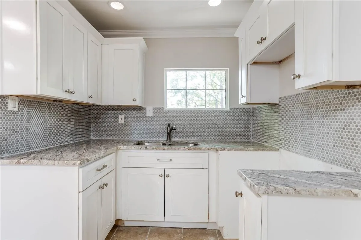 White cabinetry, stone-finish countertops, tile
flooring, recessed lighting, and a penny round tile backsplash Unit 2