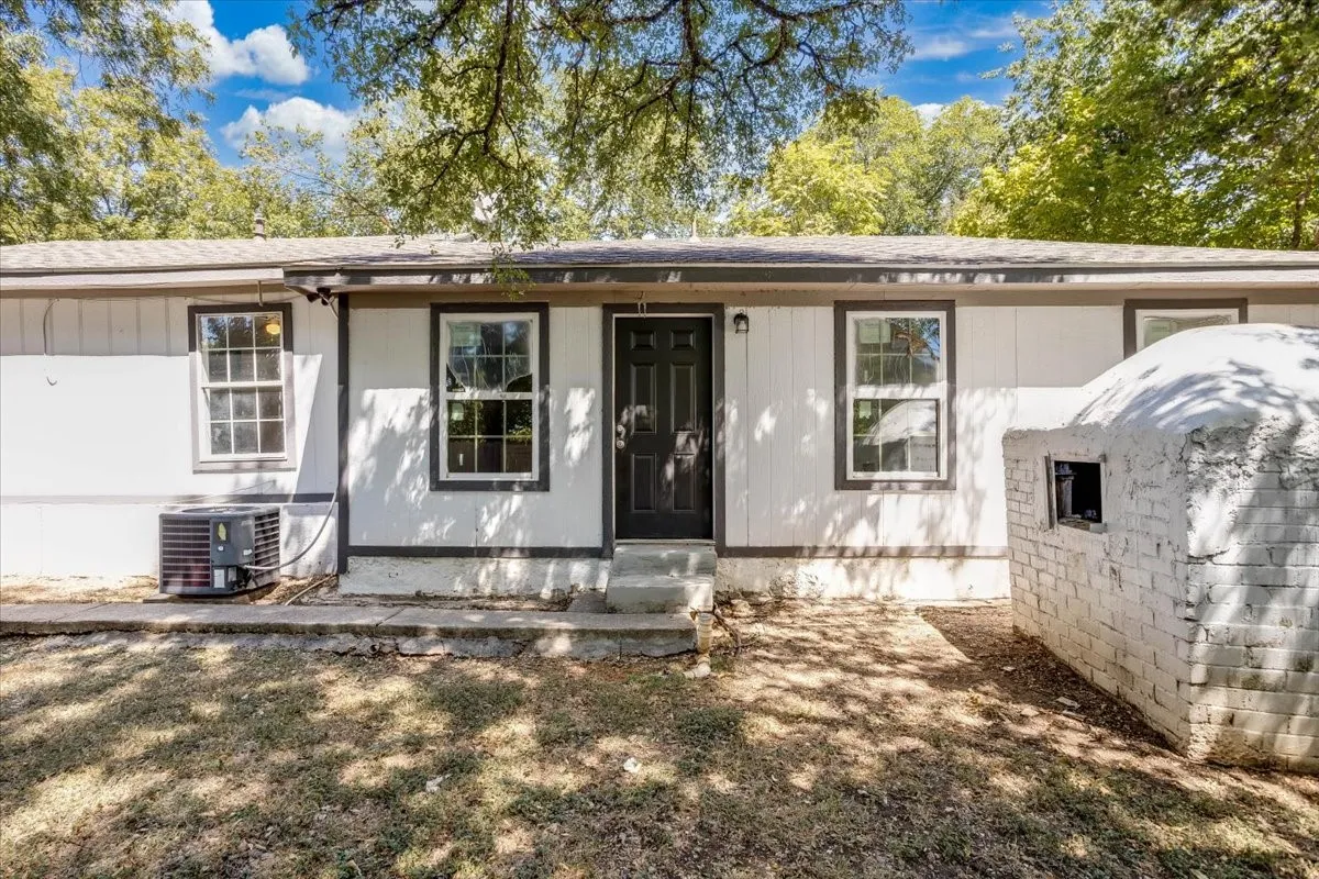 Expansive backyard featuring mature trees, a white exterior storage building, and a wood privacy fence