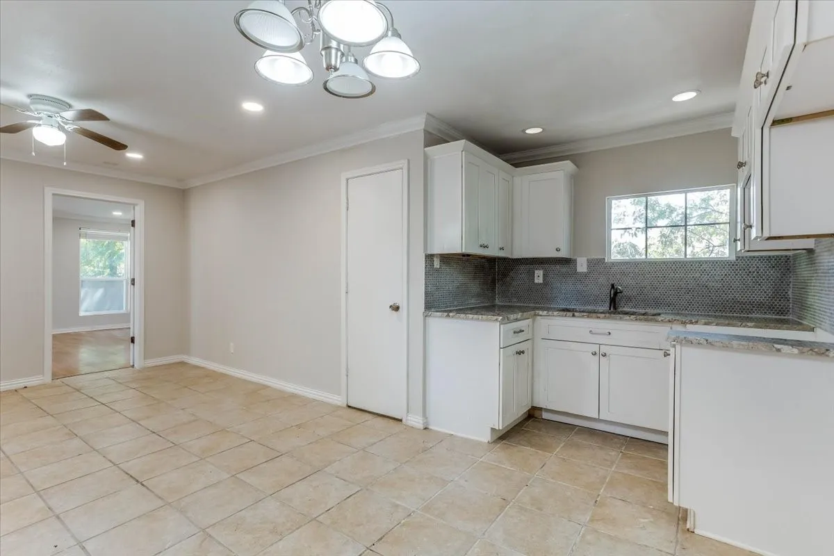 White cabinetry with brushed nickel hardware, granite countertops, and a full-height mosaic tile backsplash