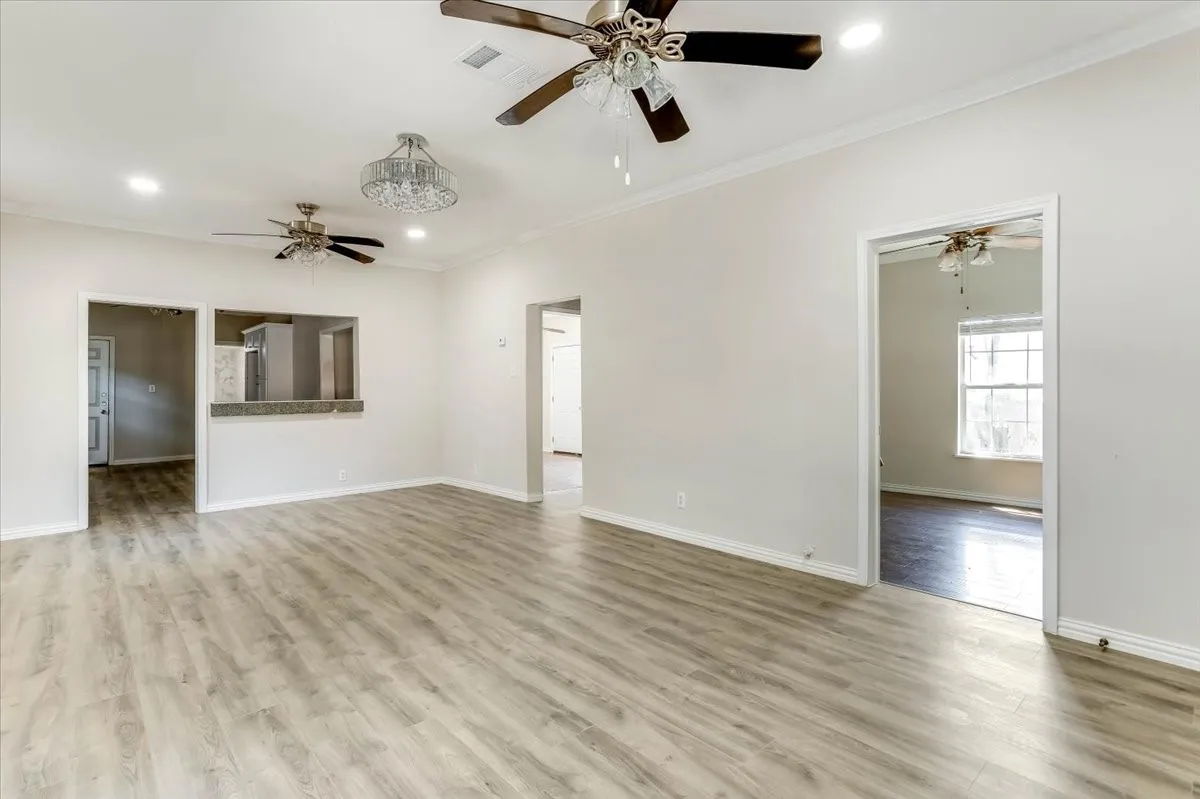 Wood-finish flooring throughout, crown molding, pass-through window with bar seating, recessed lighting, and ceiling fans