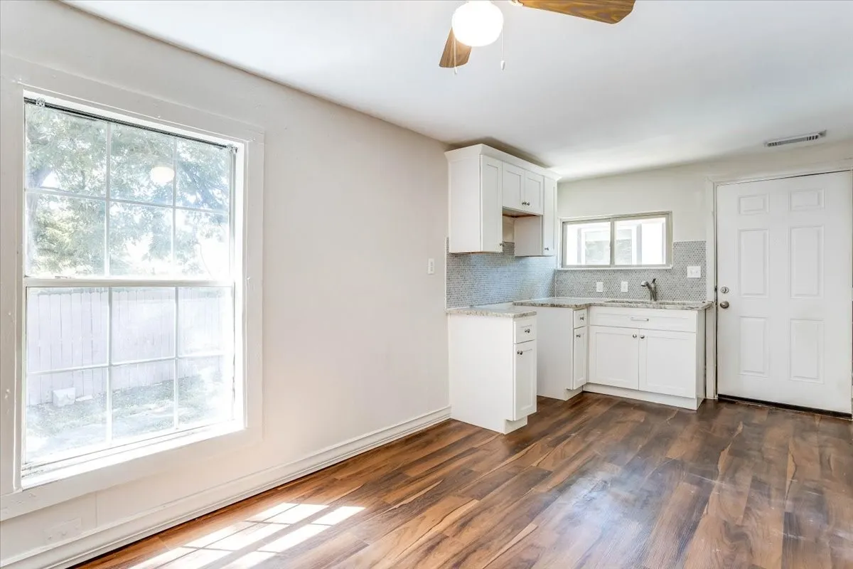 Wood-finish flooring, white cabinetry, integrated sink, tiled backsplash, and a ceiling fan with integrated lighting Unit 3
