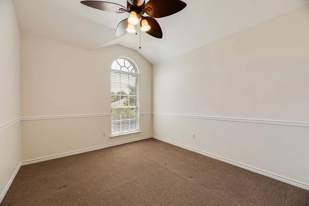 Bedroom 3, Vaulted ceiling with an attached ceiling fan, arched window with horizontal blinds, and accent wall trim