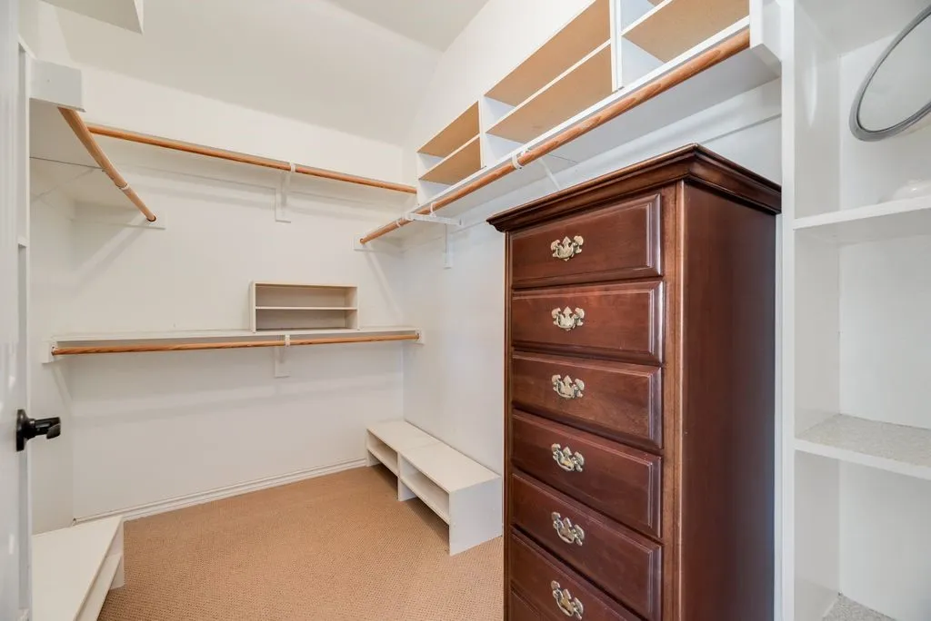 Primary Closet with Built-in shelving, multiple hanging rods, and an integrated storage bench