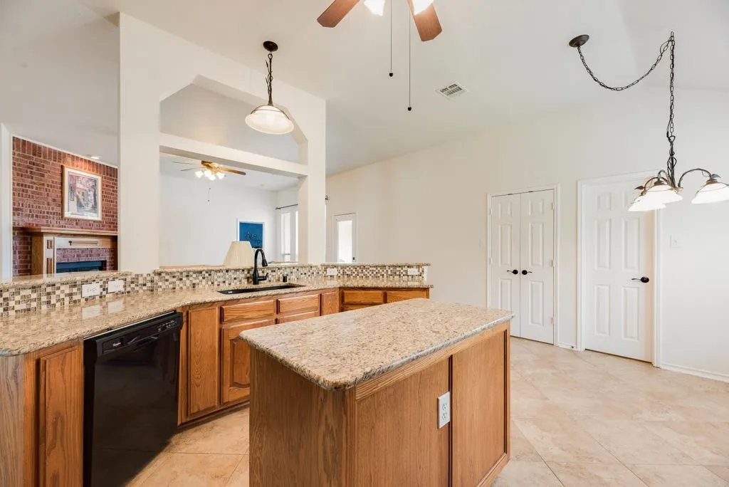 Kitchen featuring wood cabinetry, granite countertops, tile flooring, and a center island