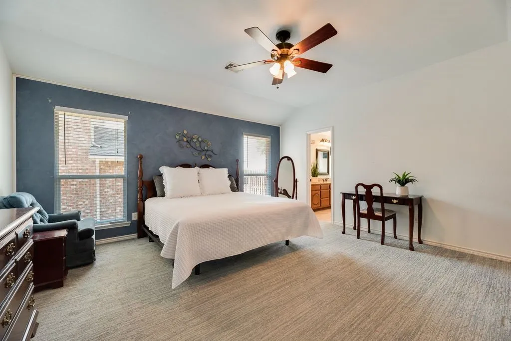Spacious room featuring vaulted ceilings, a ceiling fan, carpet flooring, and multiple windows with blinds