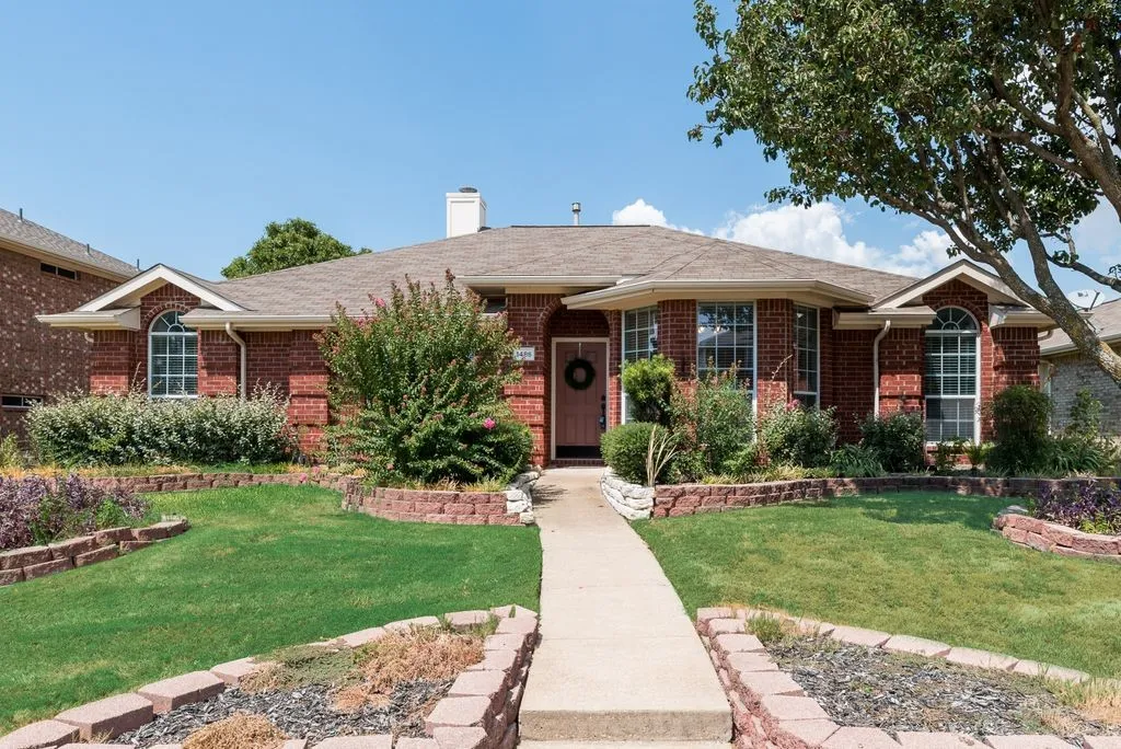 Welcoming brick exterior with arched entryways, mature landscaping, and manicured lawn