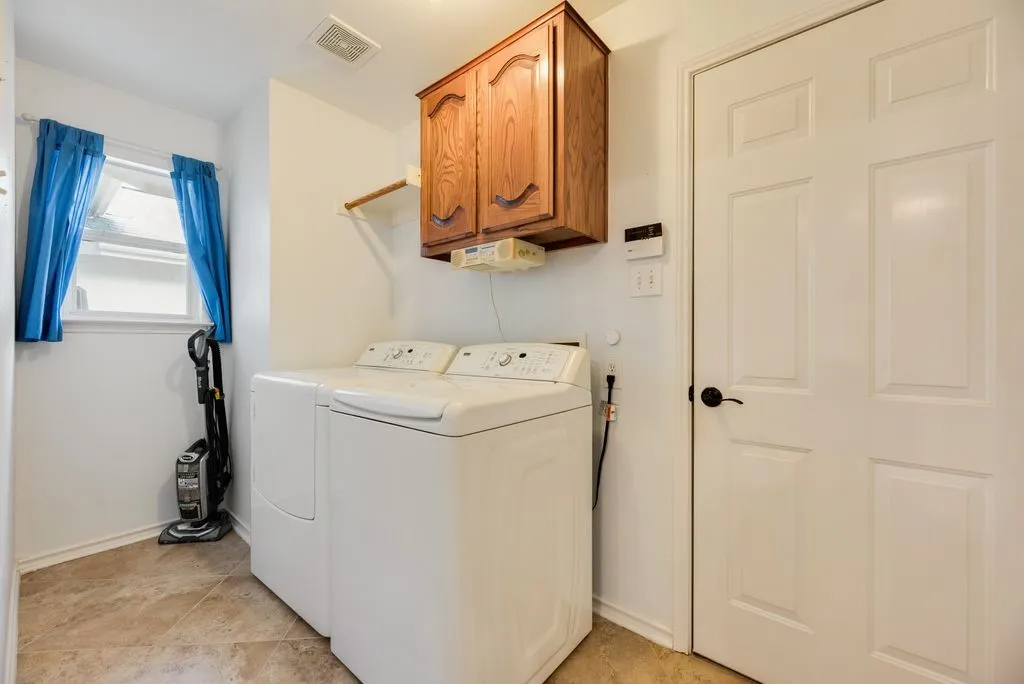 Laundry area featuring tile flooring, a window, wood cabinetry, and a white paneled door