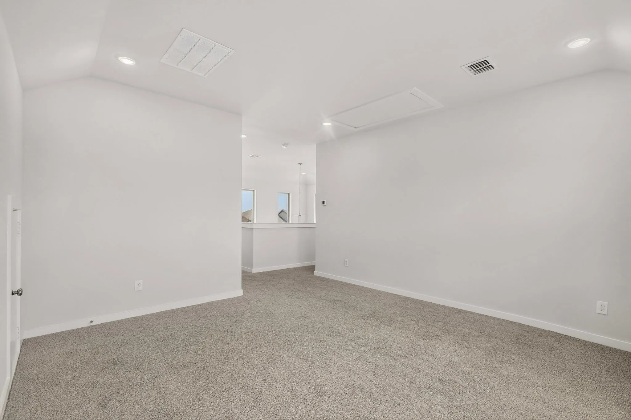 Vaulted ceilings, recessed lighting, neutral tone carpet, and a light-colored wall palette
