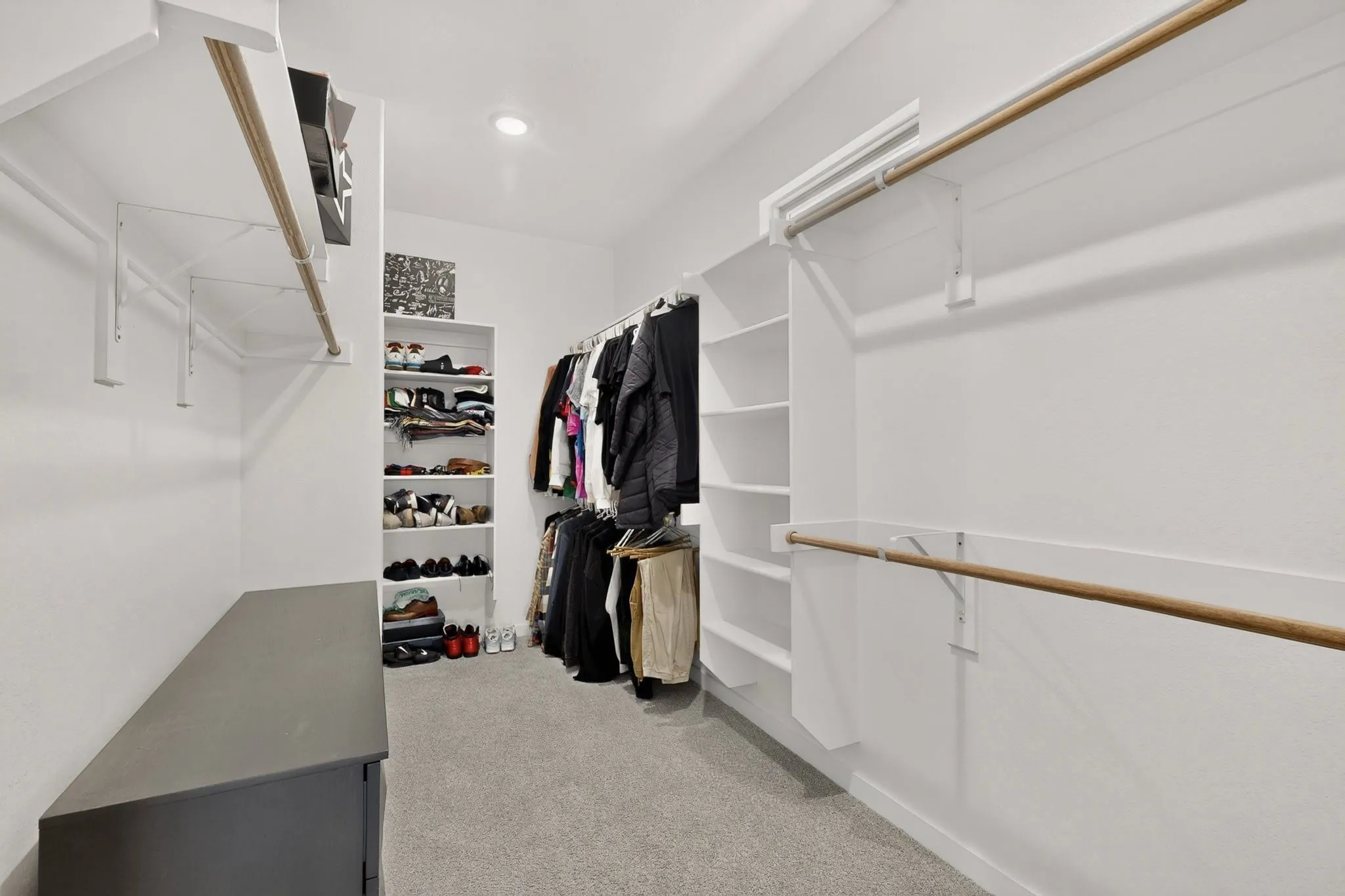 Recessed lighting illuminates the carpeted flooring and white walls