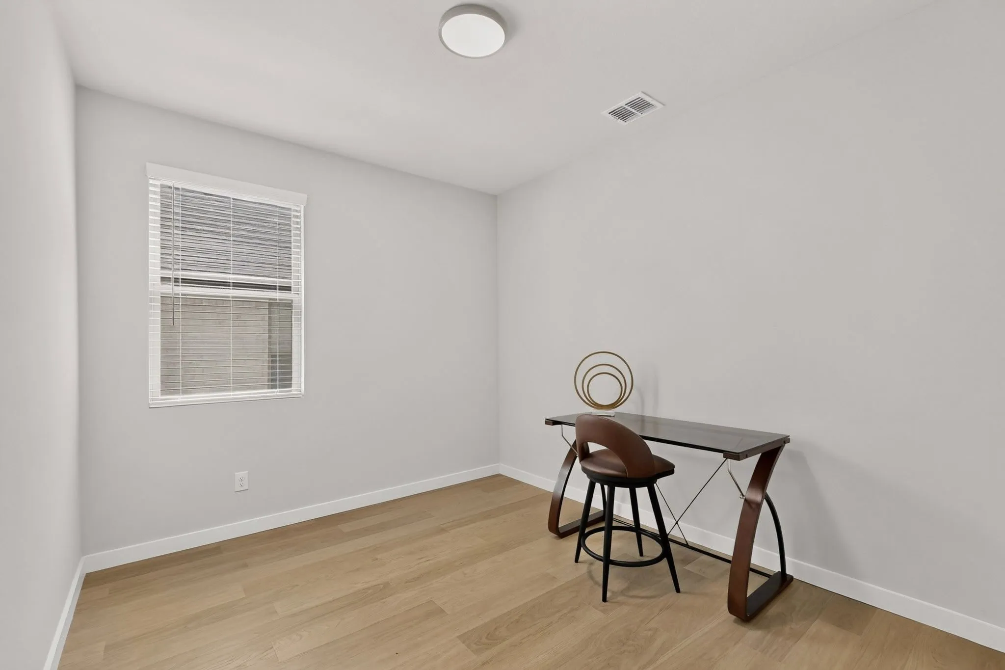 Wood-finish flooring, white walls, and a single window with blinds