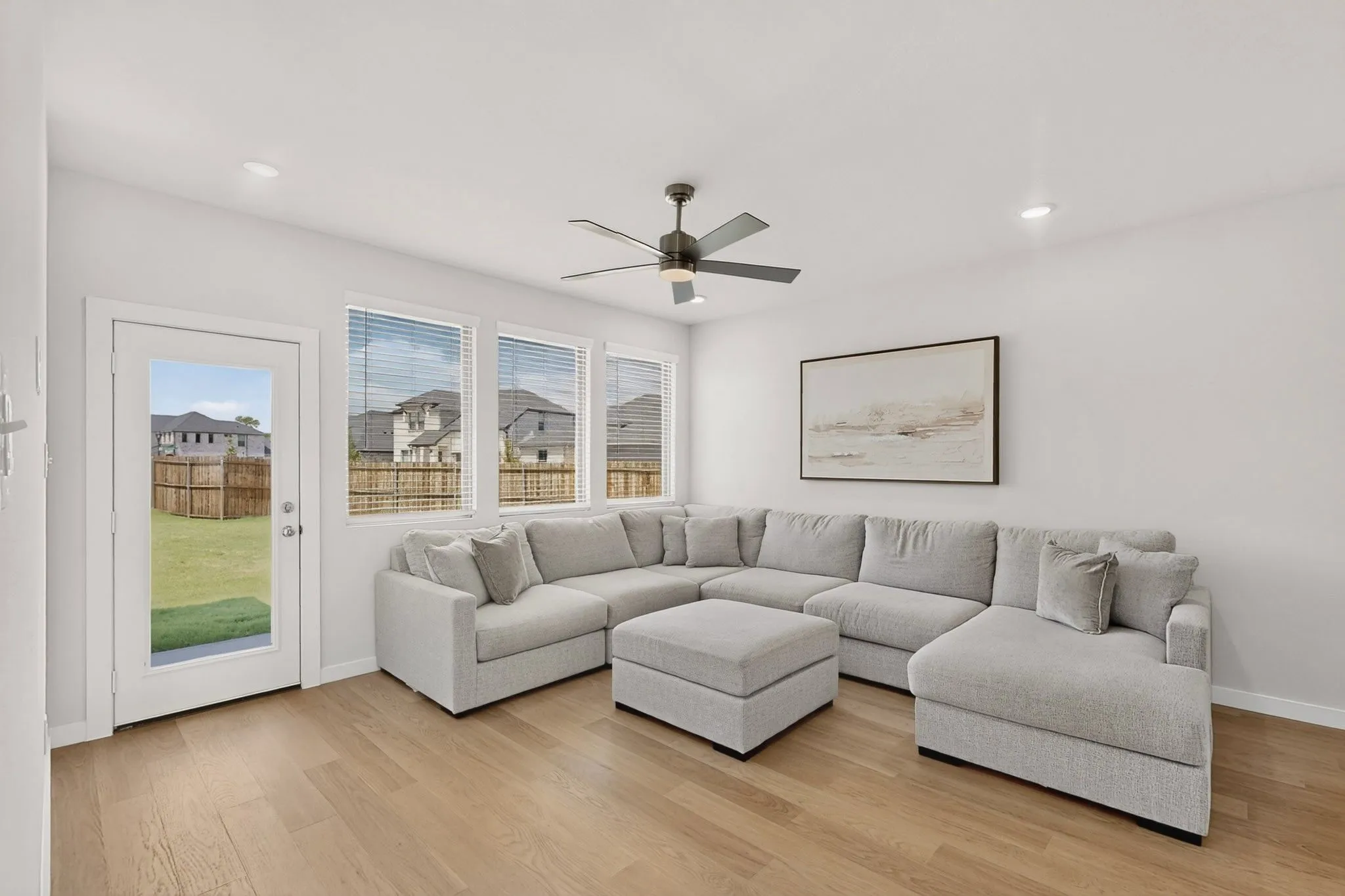 Wood-finish flooring, multiple windows with blinds, recessed lighting, and a ceiling fan with integrated lighting