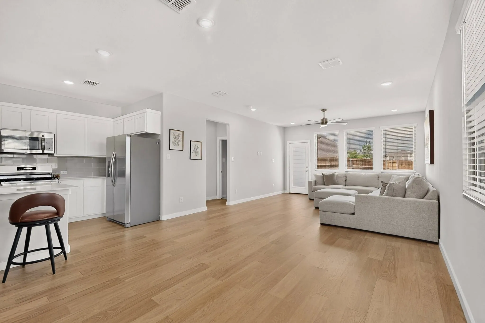 Open-concept living area featuring wood-finish flooring, recessed lighting, and a ceiling fan