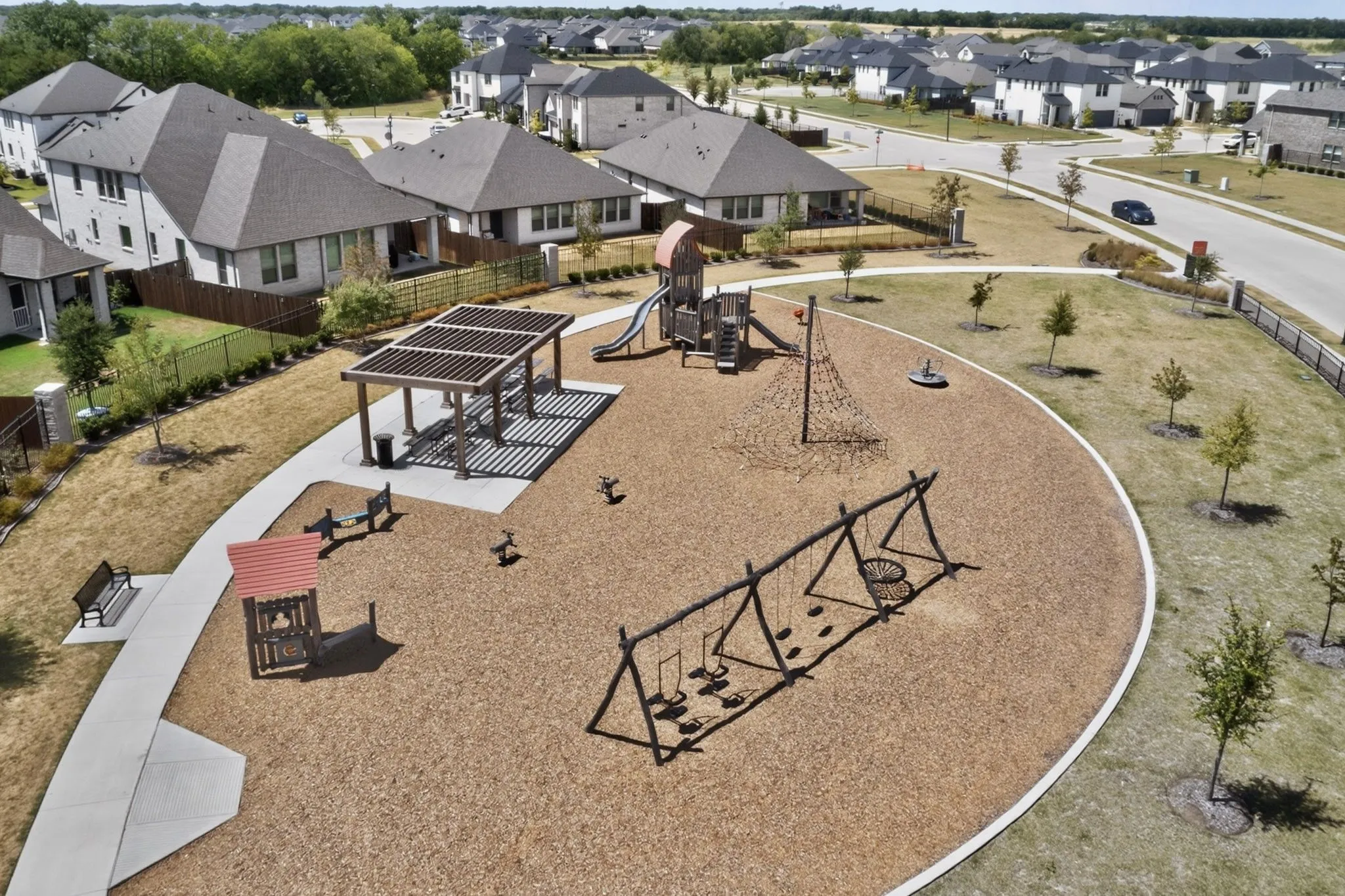 Community recreational area with a pergola, playground structure, swing set, and a network climbing feature